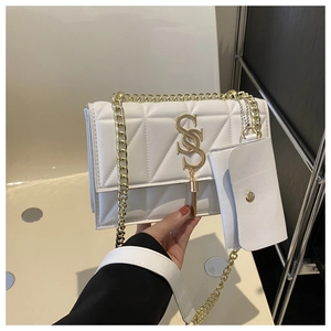 Detail of white quilted shoulder bag with gold SS logo, tassel and chain strap