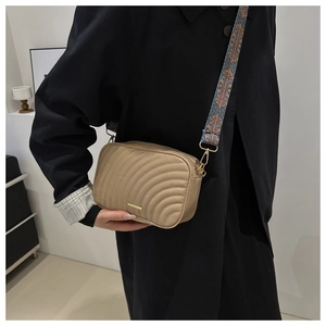 Detail of khaki quilted crossbody bag featuring ethnic style wide strap and gold hardware