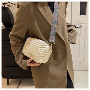 Chic beige quilted crossbody bag with a bohemian floral wide strap worn on a stylish blazer