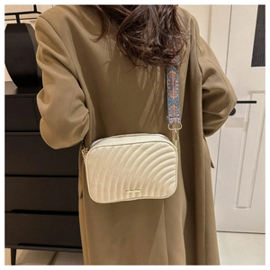 Sac caméra matelassé beige minimaliste avec large bandoulière bohème porté par un mannequin