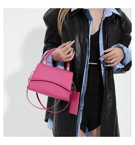 Detalle de bolso rosa intenso con textura de cocodrilo y correa de hombro desmontable