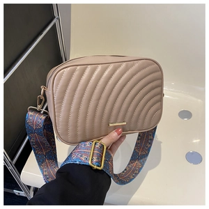 Détail sac caméra matelassé beige avec barre métallique dorée et large sangle rétro