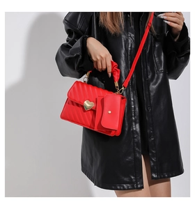 Dettaglio borsa a tracolla rossa trapuntata con fibbia a cuore dorata e mini pochette