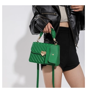 Dettaglio della borsa trapuntata verde con chiusura a cuore e manico arricciato