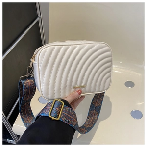 Sac caméra blanc matelassé avec large bandoulière bohème présenté à la main