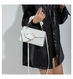 Detailed shot of white crocodile embossed handbag with gold buckle and ruched handle