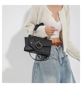 Detail of black quilted and croc-pattern handbag with gold buckle and pleated handle