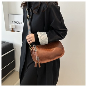 Détail d'un sac bandoulière en similicuir marron avec large sangle tissée de style ethnique