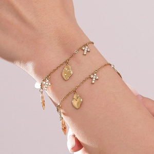 Set di bracciali dorati con cuori, croci e zirconi indossati sul polso