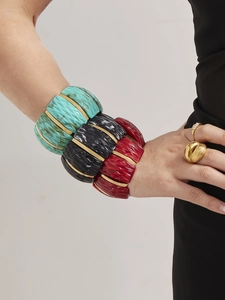 Detail of wide resin bracelets with ripple texture and 18k gold-plated metal spacers