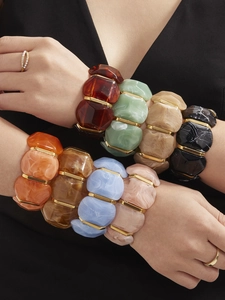 Détail de bracelets élastiques en résine marbrée en huit couleurs avec séparateurs dorés