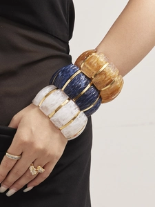 Detail of wide resin bracelets with wavy texture and gold accents in varied colors