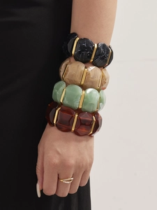 Gros plan de bracelets en résine marbrée avec détails dorés et une bague en perle