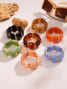 Détail de bracelets en résine multicolores avec texture marbre et séparateurs dorés