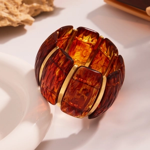Macro detail of wide amber resin elastic bracelet with 18k gold-plated metal bars