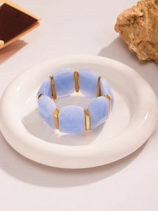 Détail du bracelet large en résine avec motifs marbrés bleus et séparateurs dorés
