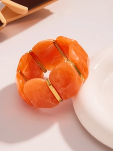 Détail du bracelet en résine marbrée orange avec des espaceurs dorés chics