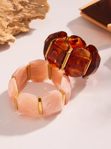 Détails de larges bracelets en résine avec textures écaillé ambre et marbre rose