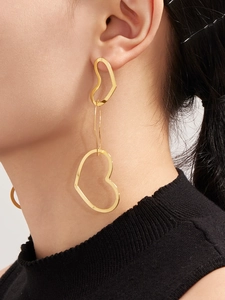 Close-up of elegant double hollow heart gold dangling earrings worn by a model
