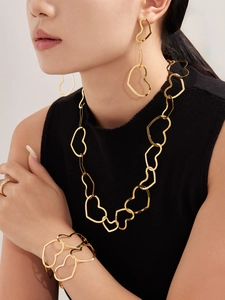 Model wearing a gold hollow heart jewelry set with necklace, earrings and bracelets