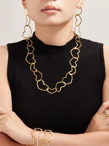 Detailed view of hollow heart-shaped gold jewelry set on model featuring necklace and earrings