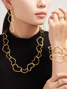 Detailed close-up of a gold-plated stainless steel hollow heart jewelry set on a model