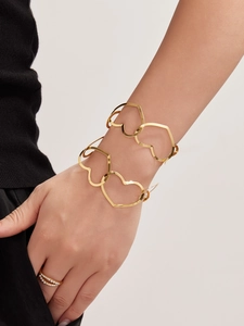 Detail of gold hollow heart bracelet set with elegant double-layered pearl ring