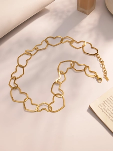 Detail of gold hollow heart chain necklace with adjustable lobster clasp on light surface