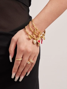 Détail d'un bracelet doré 18k avec piments en émail rouge et breloques en croix