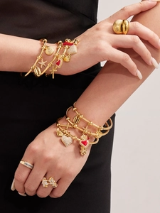 Détail de bracelets dorés avec cœurs croisés et bagues papillon en zircone
