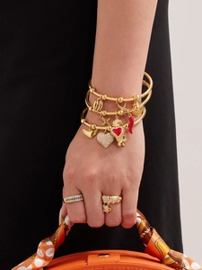 Gros plan de bracelets dorés superposés avec breloques croix et cœur pour femme