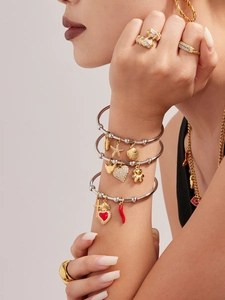 Vue détaillée de bracelets argentés superposés avec breloques croix cœur et émail coloré