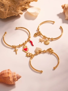Détail de bracelets joncs plaqués or 18k avec breloques croix et cœur émaillé