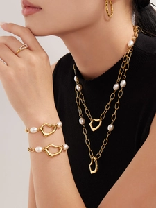 Close-up of gold-plated stainless steel jewelry set with irregular pearls on a model
