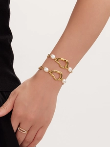 Detail of gold-plated bracelet with baroque pearls and layered pave ring on wrist