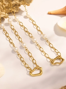 Detail of 18k gold plated necklace with pearls and irregular heart pendant on sea shell