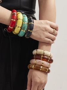Close-up of colorful resin stretch bracelets with gold spacers on a leather sleeve