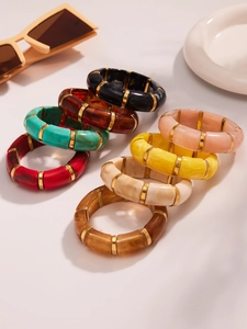 Detailed view of elastic resin bangles with gold spacers in eight diverse colors