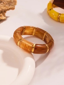 Detail of amber resin stretch bracelet with gold metal spacers and marble texture