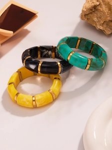 Detailed stack of three elastic resin bracelets in yellow, black and green marble