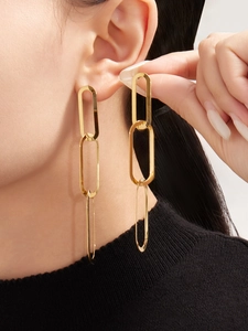 Gros plan sur des boucles d'oreilles géométriques dorées portées par un mannequin en noir