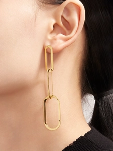 Gros plan d'élégantes boucles d'oreilles pendantes dorées à trois maillons sur un mannequin