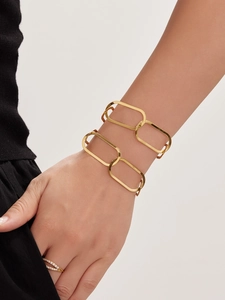 Gros plan du bracelet à maillons rectangulaires dorés 18k et bague en zircons sur mannequin