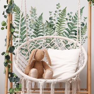 Detail of green fern wall stickers behind a bohemian swing chair with plush bunny décor