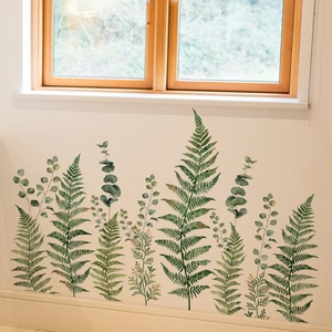 Detail of watercolor green fern and eucalyptus wall stickers on a white interior wall