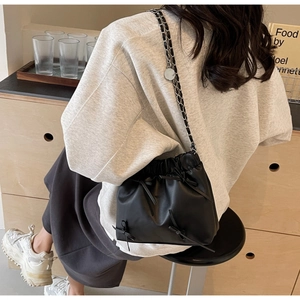 Detail of black drawstring bucket bag with silver chain strap and bow decorations