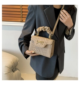 Detail of beige square handbag with geometric texture and ruffled cloud handle