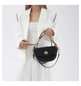 Detail of black saddle bag with gold clasp and silk scarf wrapped chain handle
