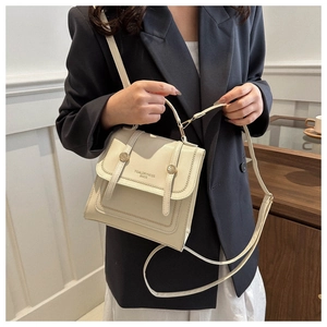 Detail of a creamy white messenger bucket bag with gold buckles and adjustable strap