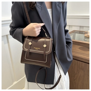 Detail of dark brown vintage messenger bag with gold brand logo and delicate white stitching